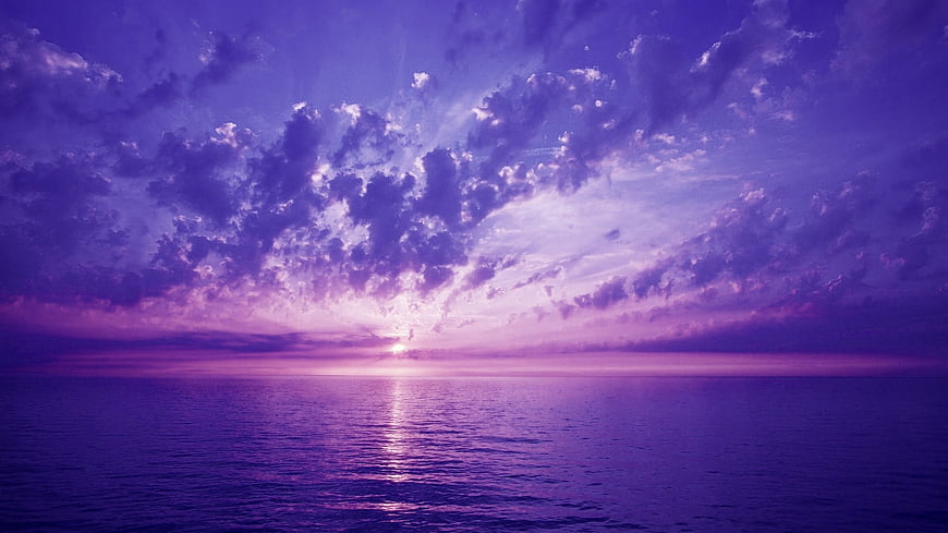 Dramatic Purple Sunset Over Calm Ocean with Clouds