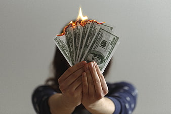 Hands holding burning hundred dollar bills