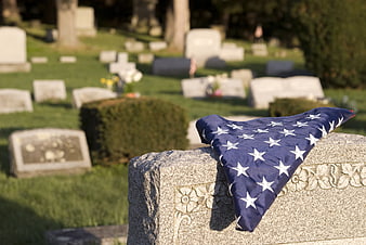 Folded American flag on granite headstone in cemetery