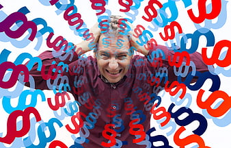 Stressed man overwhelmed by floating dollar signs and financial pressure