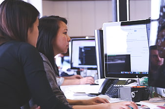 Two Women Working at Computer Monitors in Office