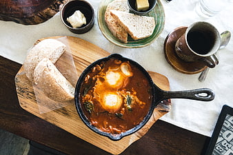 Top view of shakshuka skillet with bread and coffee