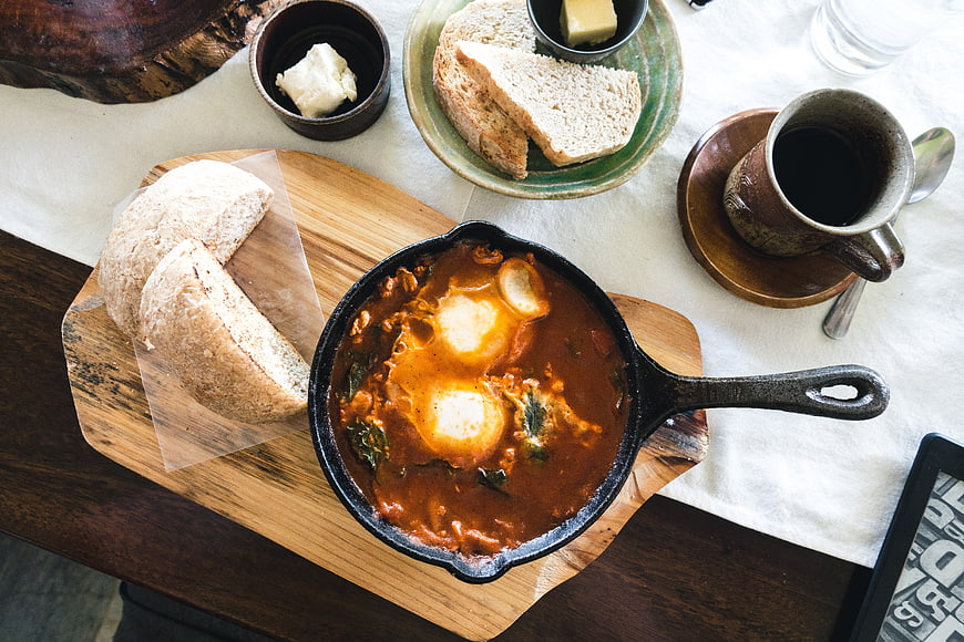 Top view of shakshuka skillet with bread and coffee