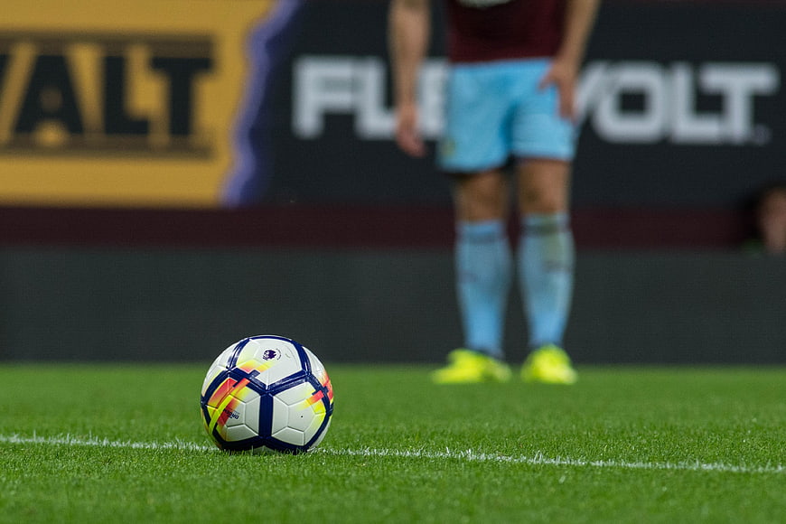 Soccer Ball on Grass Pitch with Blurred Player