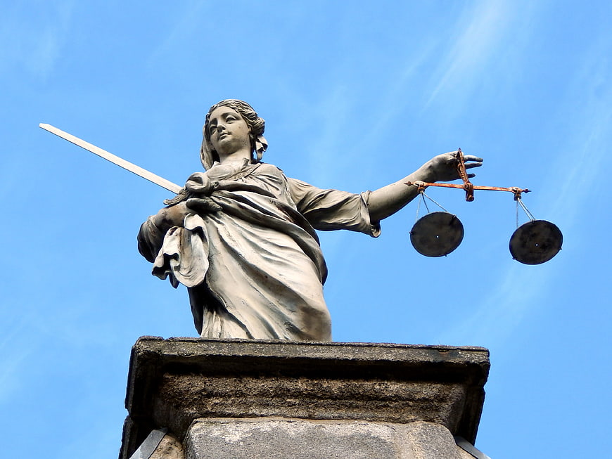 Statue of Lady Justice with Sword and Scales Against Blue Sky