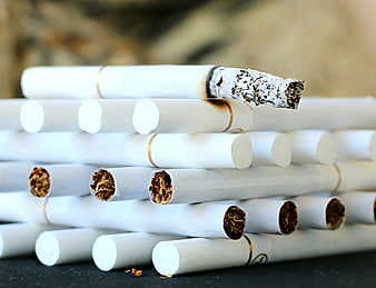 Stack of Cigarettes with Burnt Tip and Exposed Tobacco