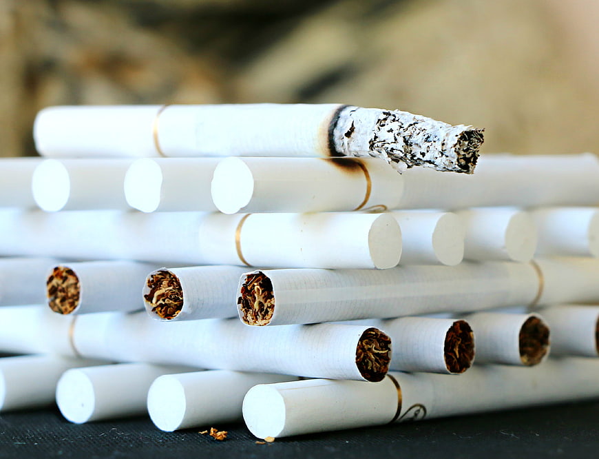 Stack of Cigarettes with Burnt Tip and Exposed Tobacco