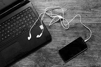 Black and white laptop and smartphone with earphones on wood