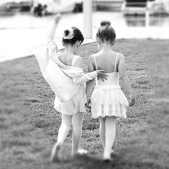 Two young ballerinas walking away on grass in black and white