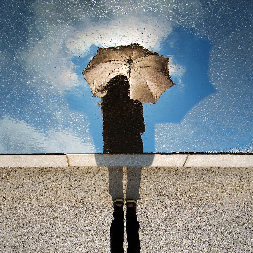 Creative Reflection of Woman with Umbrella in Pool Water