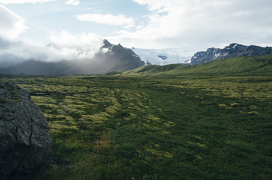 Mossy tundra landscape with distant glacier and mountains