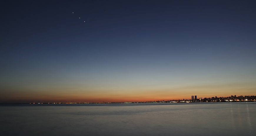 Serene Twilight Cityscape Over Calm Ocean Water