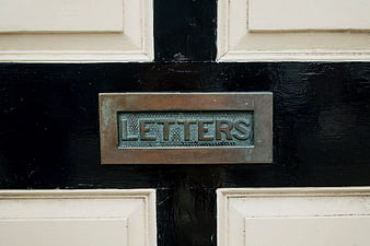 Close-up of vintage brass letterbox on black and white door