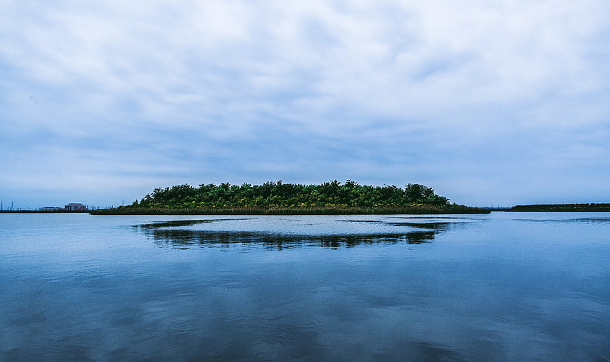 Serene island with lush trees reflected in calm blue water