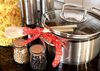 Stainless steel pot with wooden spoon and red ribbon on kitchen counter