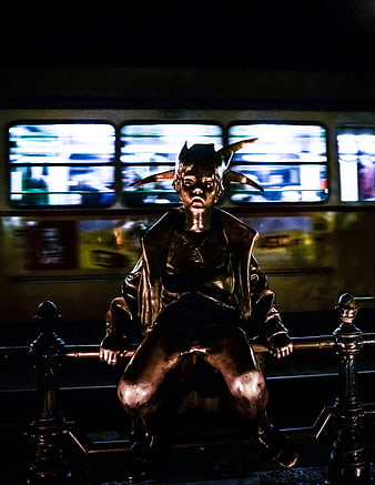 Bronze Joker Statue Sitting on Bench with Blurred Tram Background