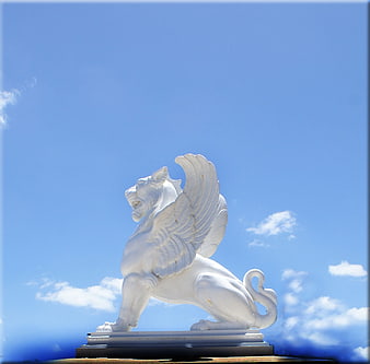 White Winged Lion Statue Against Blue Sky