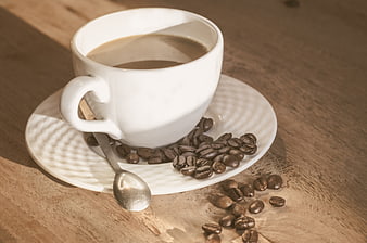 White Coffee Cup with Beans on Wooden Table