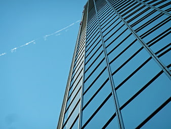Low angle view of modern glass skyscraper against blue sky