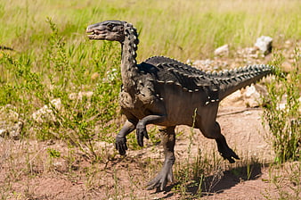 Life-size dinosaur model running in grassy field