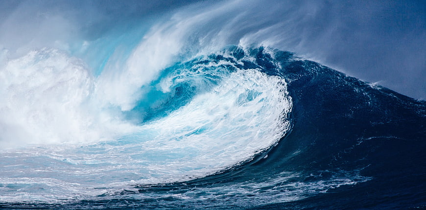 Powerful ocean wave crashing with white spray and blue water