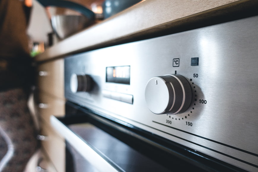 Close-up of stainless steel oven control knob and temperature dial