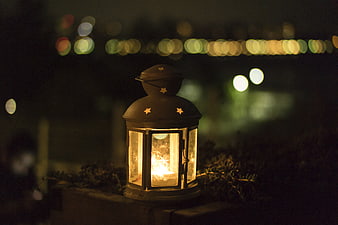Glowing Lantern with Star Cutouts Against Night Bokeh