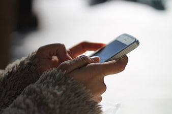 Close-up of hands texting on smartphone in winter
