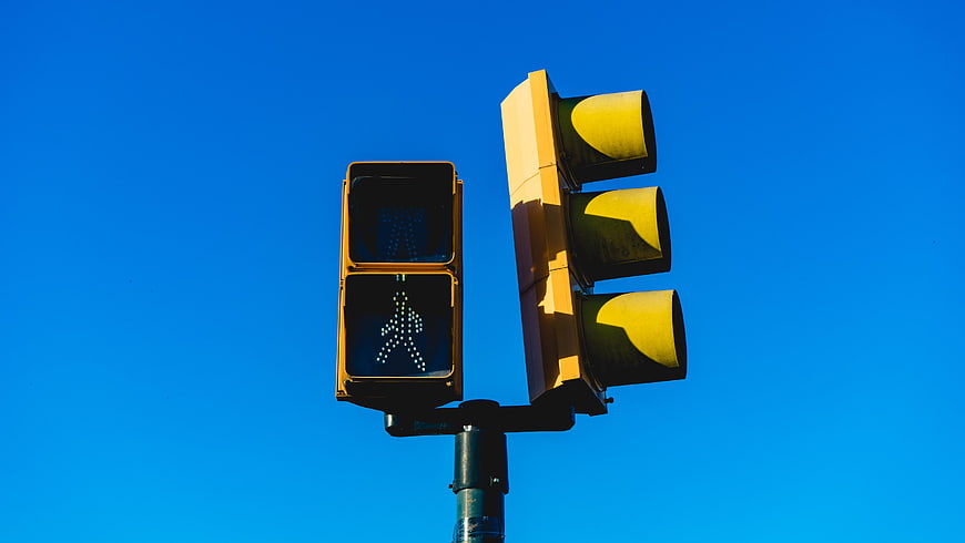 Yellow Traffic Light and Pedestrian Signal Against Blue Sky