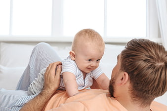 Happy Father Playing with Baby on Bed