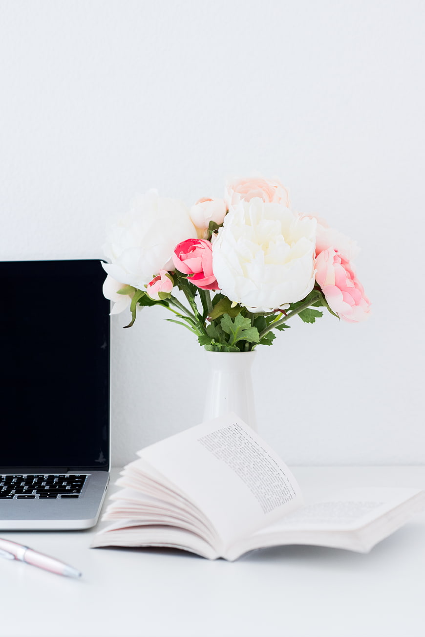 Minimalist White Desk Setup With Laptop, Open Book, And Pink Peony Bouquet