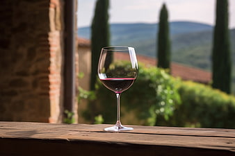 Glass of red wine on wooden table with Tuscan landscape background