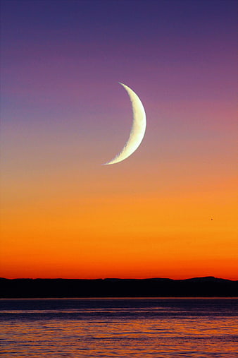 Crescent Moon Over Ocean Horizon At Sunset
