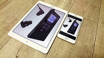 White iPad and iPhone displaying music player on wooden floor