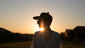 Silhouette of Woman in Cap at Sunset