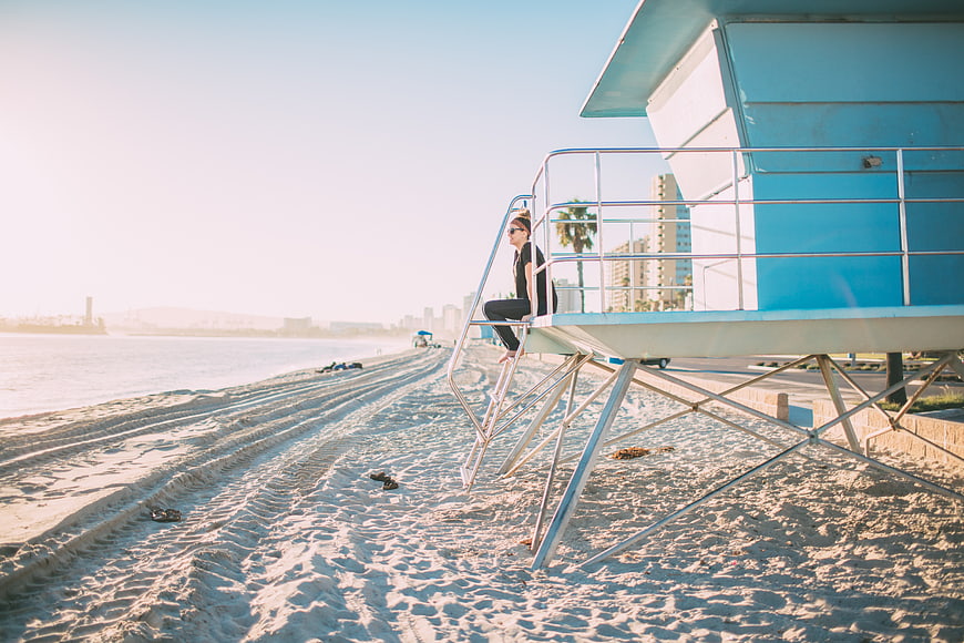 Woman Sitting on Blue Lifeguard Tower at Beach