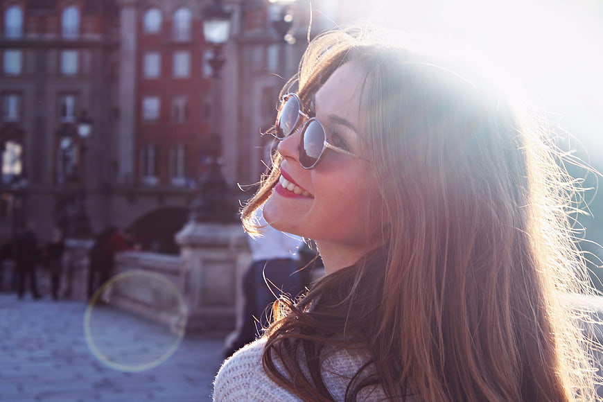 Happy woman with sunglasses smiling in city square