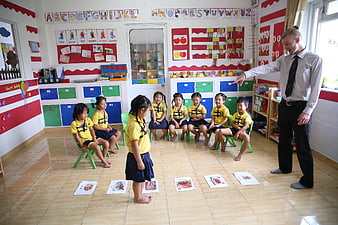 Teacher Leading English Lesson With Young Children In Kindergarten Classroom