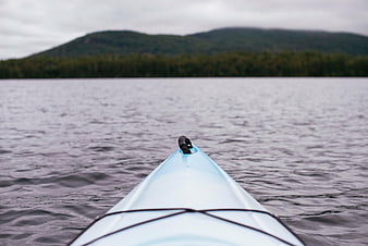 Blue Kayak Bow on Calm Lake with Mountain Background