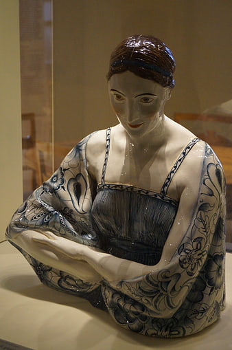 Blue and white ceramic sculpture of a seated woman