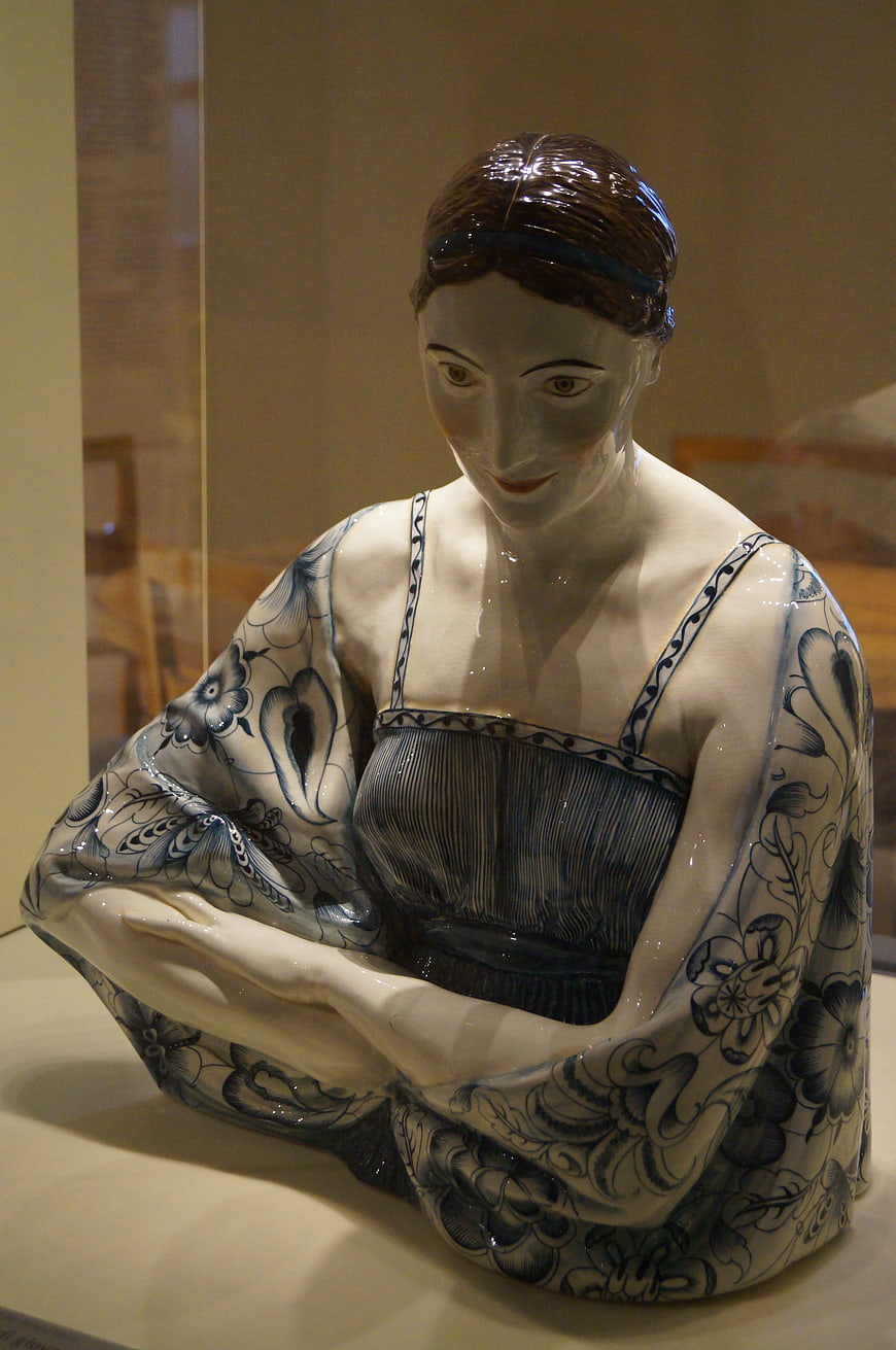 Blue and white ceramic sculpture of a seated woman