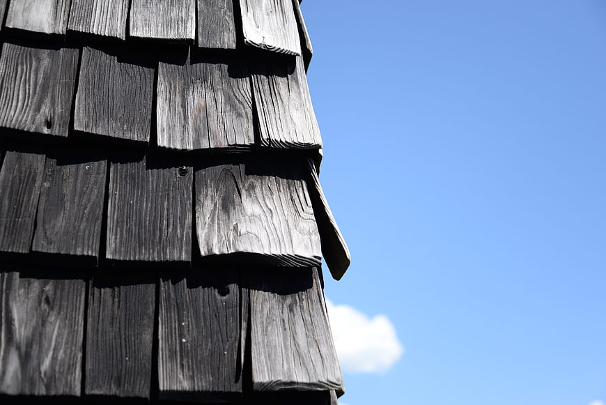 Weathered wooden shingles on a roof against blue sky