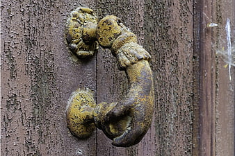 Rusty vintage door knocker on weathered wooden door
