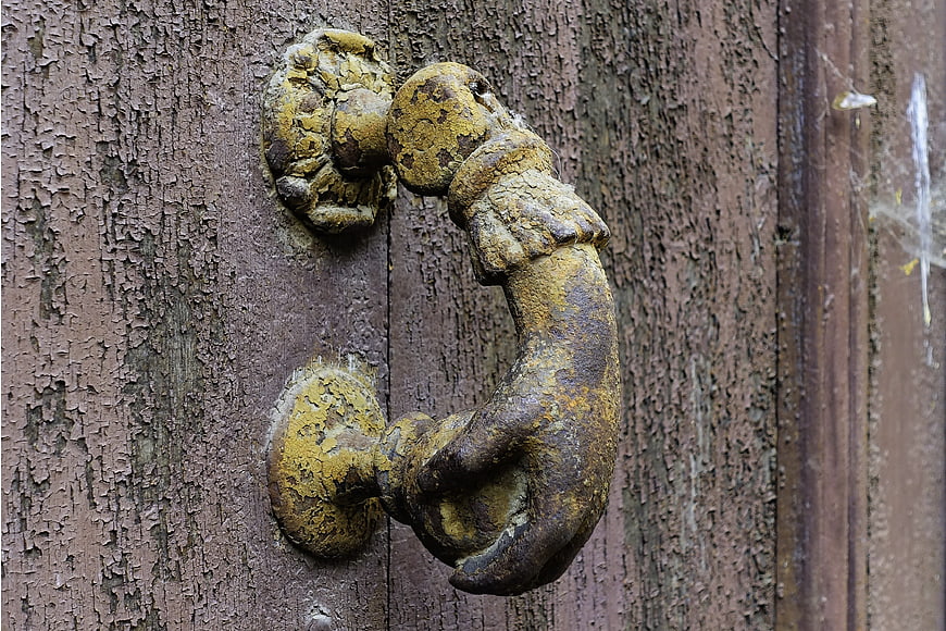 Rusty vintage door knocker on weathered wooden door