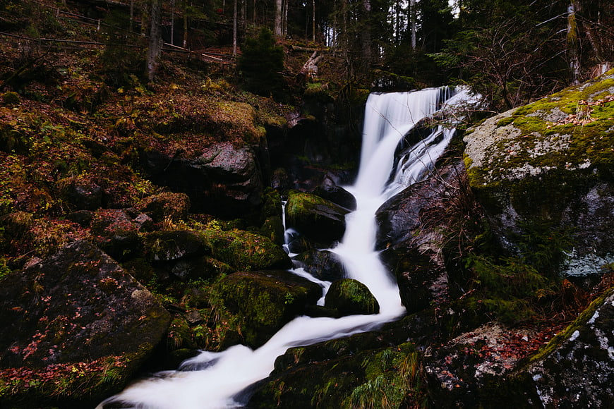 Misty Waterfall Cascading Through Mossy Forest Rocks