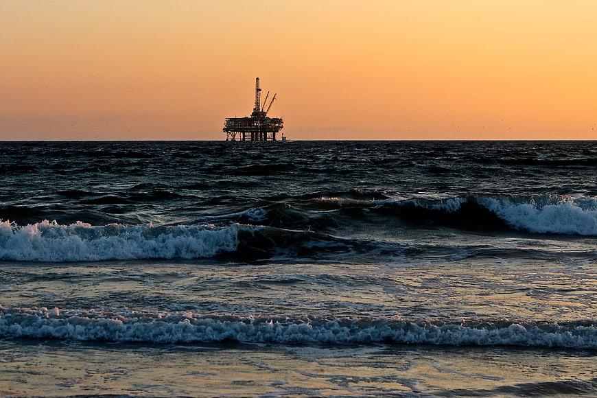 Offshore Oil Rig Silhouette on Ocean Horizon at Sunset
