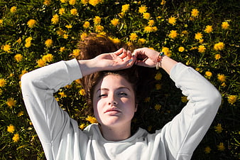 Young woman lying in field of yellow dandelions