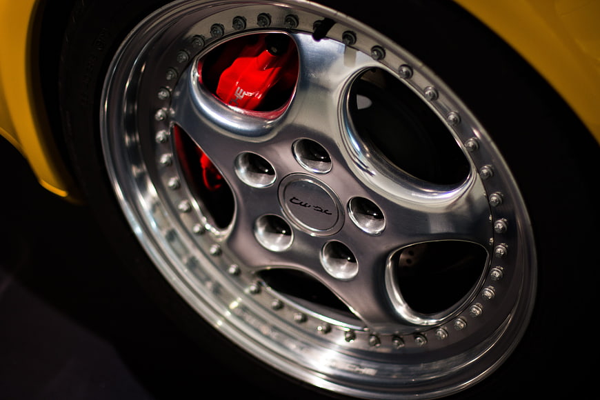Close-up of silver car wheel with red brake caliper