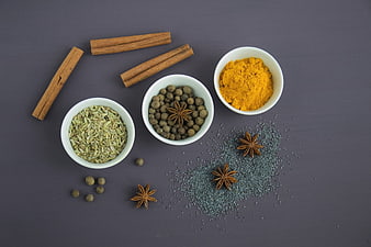 Top view of cinnamon, turmeric, fennel, and spices on dark background