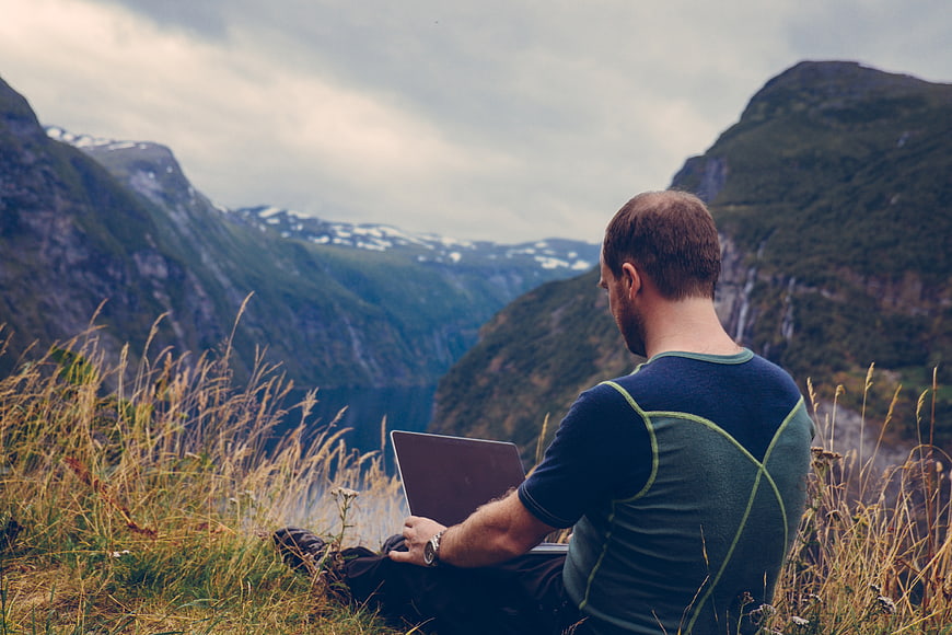 Man Working on Laptop in Mountain Landscape